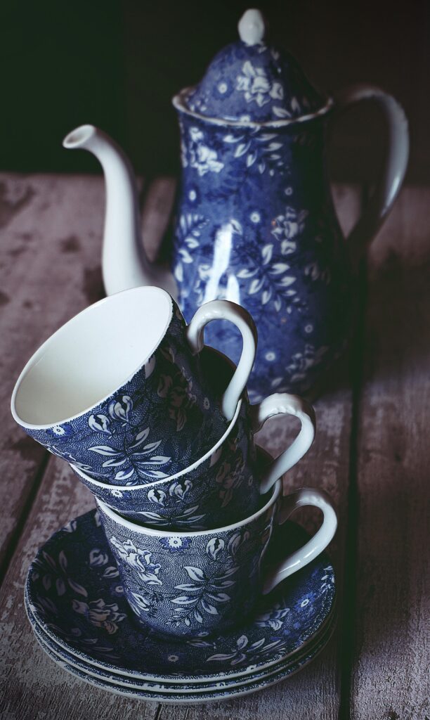 Elegant blue floral porcelain tea set with teapot and teacups on a rustic table.