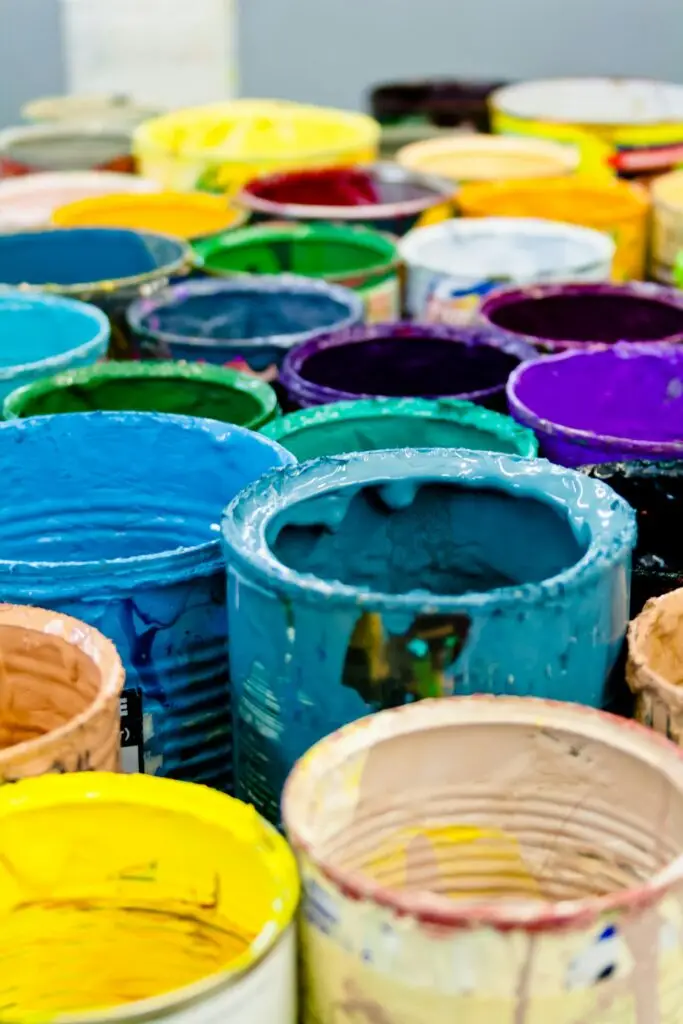 A vivid assortment of open paint cans displaying a spectrum of colors, ideal for artistic and design projects.